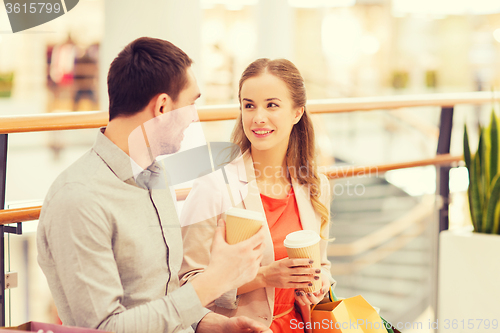 Image of happy couple with shopping bags drinking coffee