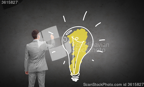 Image of businessman drawing lighting bulb from back