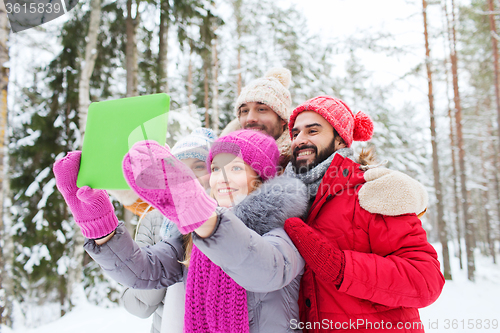 Image of smiling friends with tablet pc in winter forest