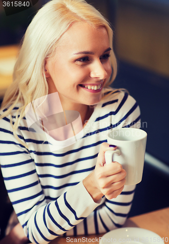 Image of happy young woman drinking tea or coffee