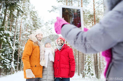 Image of smiling friends with tablet pc in winter forest