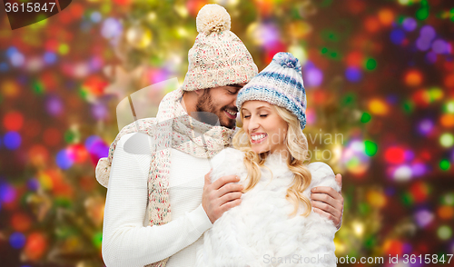 Image of happy couple in winter clothes hugging over lights