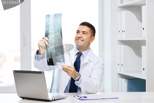 Image of smiling male doctor in white coat looking at x-ray