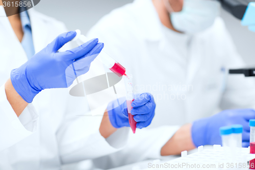 Image of close up of scientists hands with test tube in lab