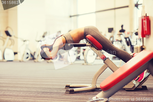 Image of young woman flexing back muscles on bench in gym