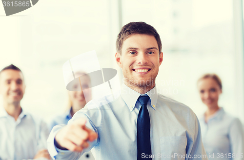 Image of smiling businessman with colleagues in office