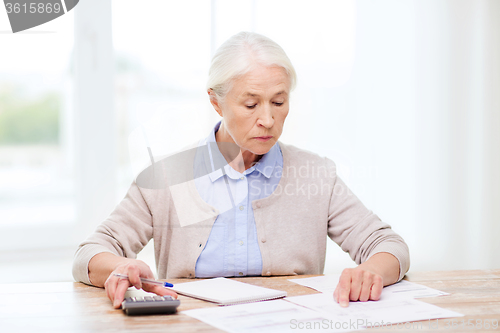 Image of senior woman with papers and calculator at home