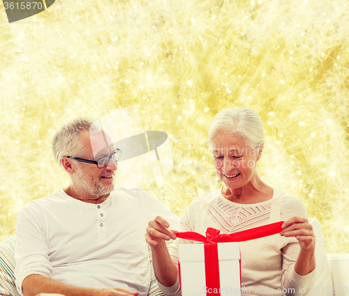 Image of happy senior couple with gift box at home