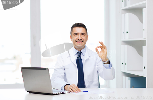 Image of smiling doctor with laptop showing ok in office