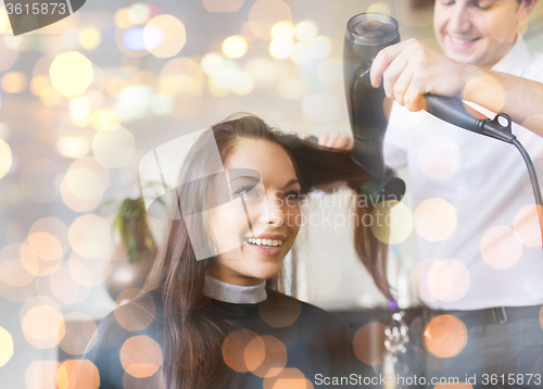 Image of happy woman with stylist making hairdo at salon