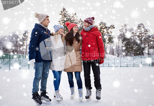 Image of happy friends ice skating on rink outdoors