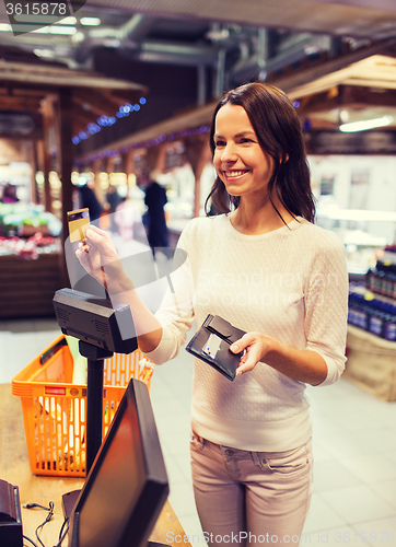 Image of happy woman with credit card buying food in market