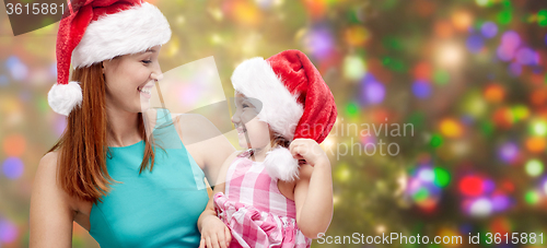 Image of happy mother and little girl in santa hats