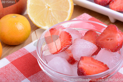 Image of A slice of red strawberry on glass plate with lemon and mandarin in party theme background