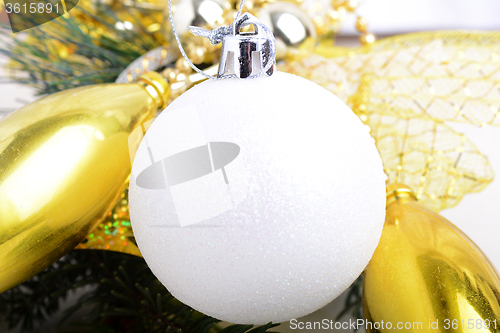 Image of festive golden christmas decoration, candles, white balls, green fir tree branch, close up