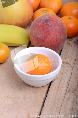 Image of Mandarin Apples Bananas Peach on wooden plate