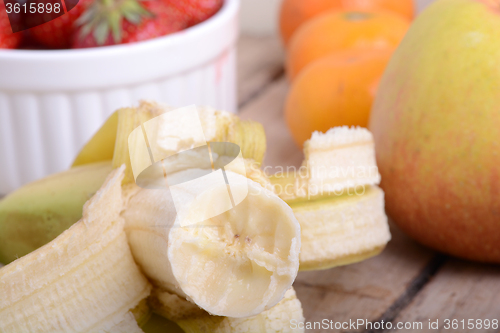 Image of Bananas apple mandarin peach strawberry on wooden background as health food concept