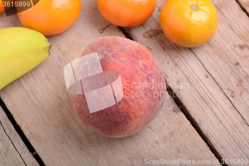 Image of Bananas apple mandarin peach strawberry on wooden background as health food concept