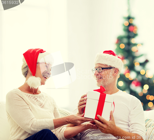 Image of happy senior couple with gift box at home