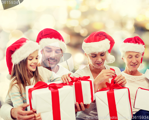 Image of happy family in santa helper hats with gift boxes