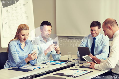 Image of smiling business people with gadgets in office