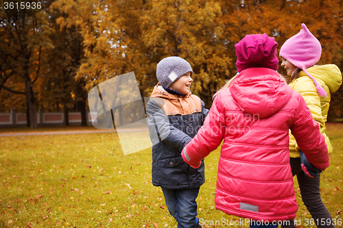 Image of children holding hands and playing in autumn park