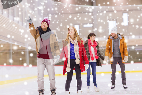 Image of happy friends pointing finger on skating rink