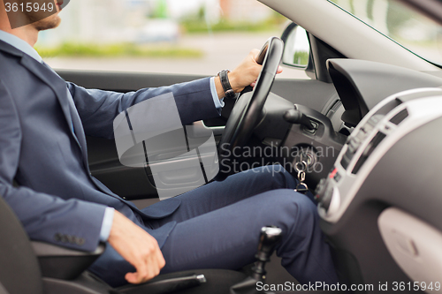 Image of close up of young man in suit driving car