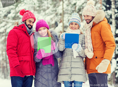 Image of smiling friends with tablet pc in winter forest