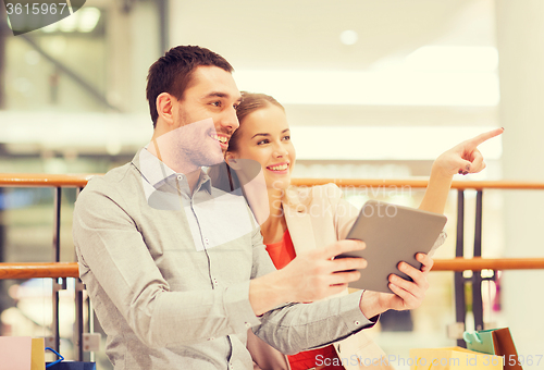 Image of couple with tablet pc and shopping bags in mall