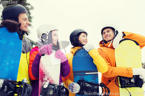 Image of happy friends in helmets with snowboards talking