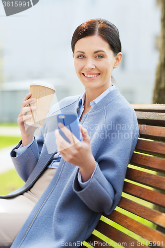 Image of smiling woman with coffee and smartphone