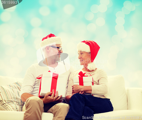 Image of happy senior couple in santa hats with gift boxes
