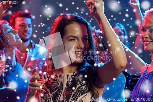 Image of smiling friends with glasses of champagne in club