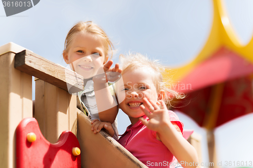 Image of happy girls waving hands on children playground