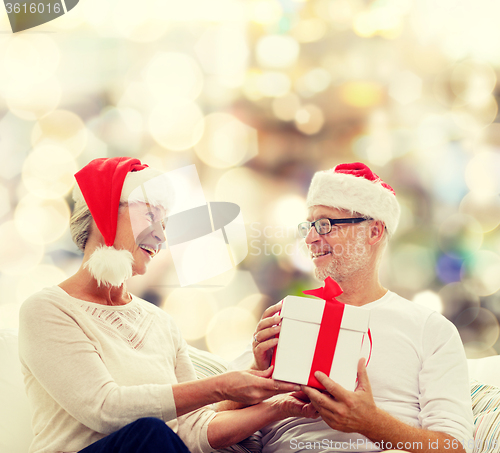 Image of happy senior couple with gift box at home