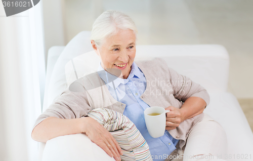 Image of happy senior woman with cup of tea at home