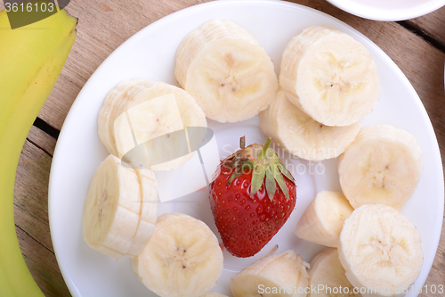 Image of healthy strawberry and bananas slices on wooden background