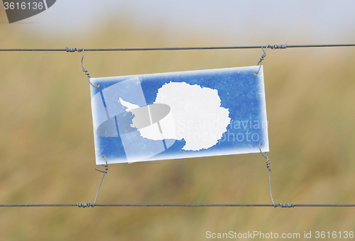 Image of Border fence - Old plastic sign with a flag