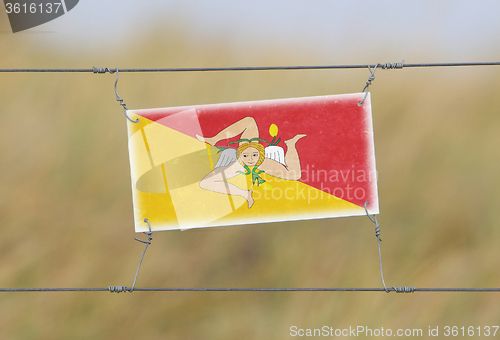 Image of Border fence - Old plastic sign with a flag