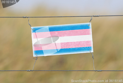 Image of Border fence - Old plastic sign with a flag