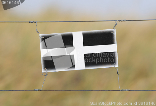 Image of Border fence - Old plastic sign with a flag