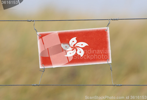 Image of Border fence - Old plastic sign with a flag