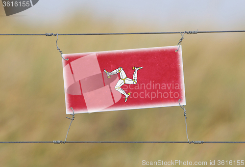 Image of Border fence - Old plastic sign with a flag