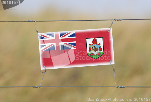 Image of Border fence - Old plastic sign with a flag