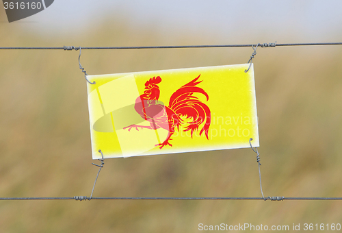 Image of Border fence - Old plastic sign with a flag