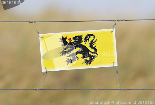 Image of Border fence - Old plastic sign with a flag