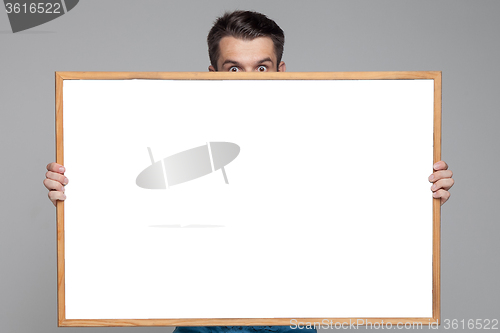 Image of The surprised man showing empty white billboard or banner on gray background