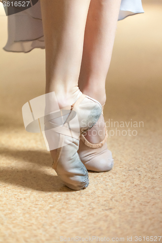 Image of The close-up feet of young ballerina in  old pointe shoes 