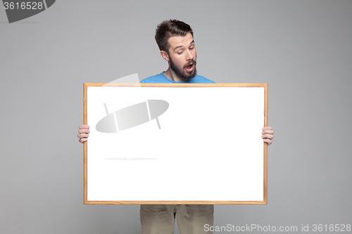 Image of The surprised man showing empty white billboard or banner 